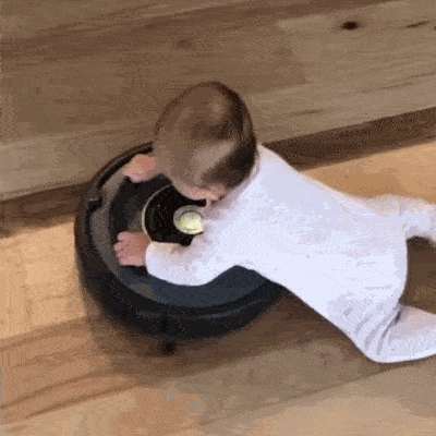 enfant  accroché à un robot aspirateur en mouvement